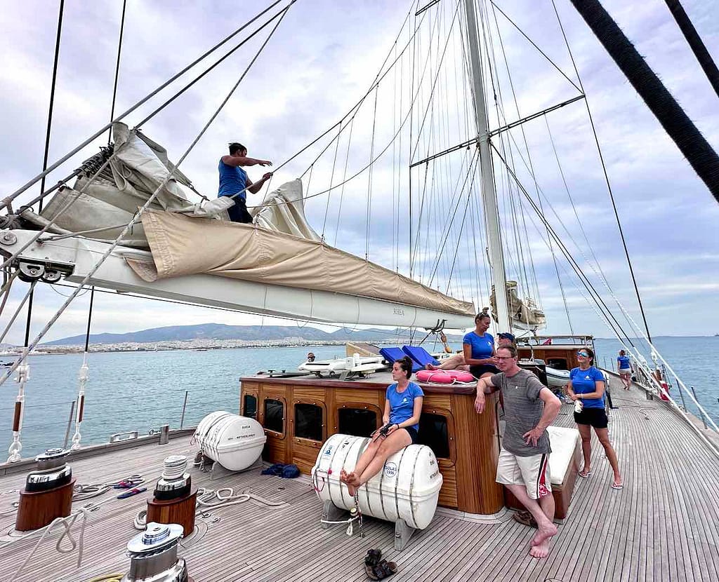 Segelyacht Rhea: Crew-Mitglied beim Segelreffen. Zuschauende Passagiere. © PetersTravel Peter Pohle