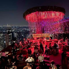 Bangkok: Festlich beleuchtete Tichuca Rooftop Bar mit dem nächtlichen Bangkok im Hintergrund